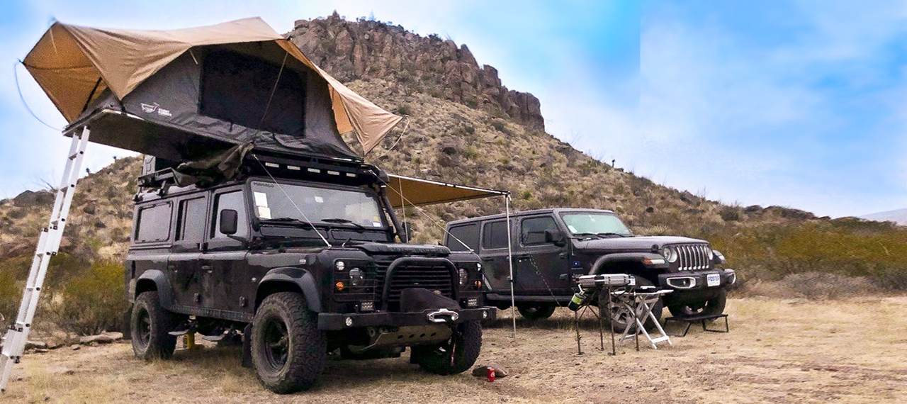 A Land Rover Defender with roof-top tent and Jeep Wrangler
