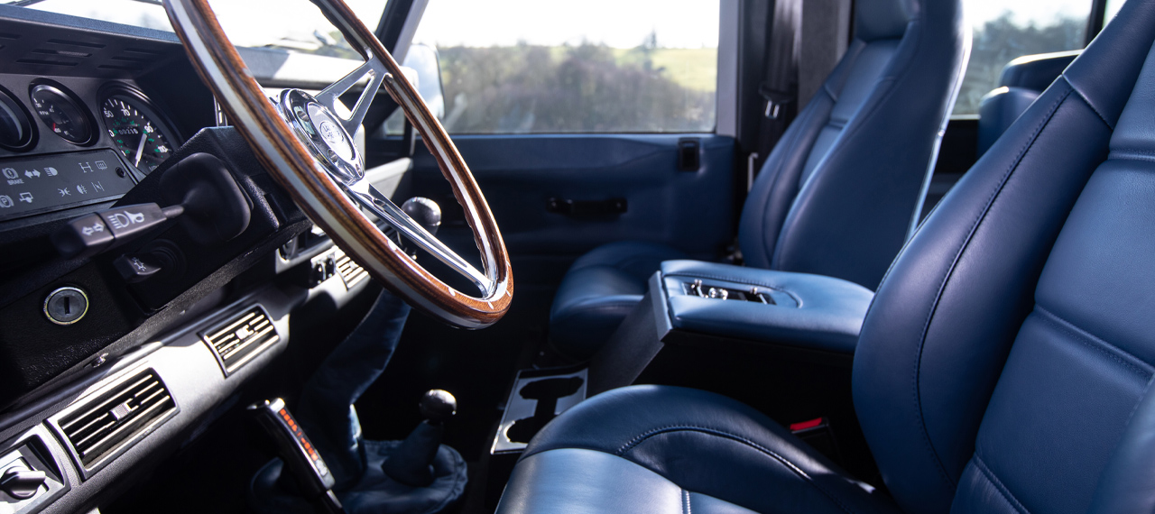 Blue leather Defender interior with wooden steering wheel