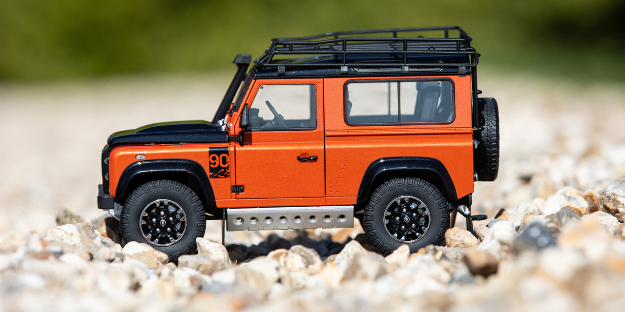 Side view of a small orange and black model of a Defender