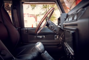 Internal side view of a Land Rover Defender driver door and steering wheel.