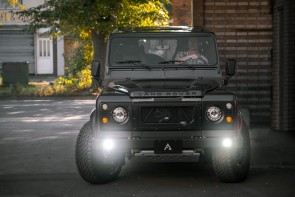 Man driving an Arkonik Land Rover Defender with DRLs on.