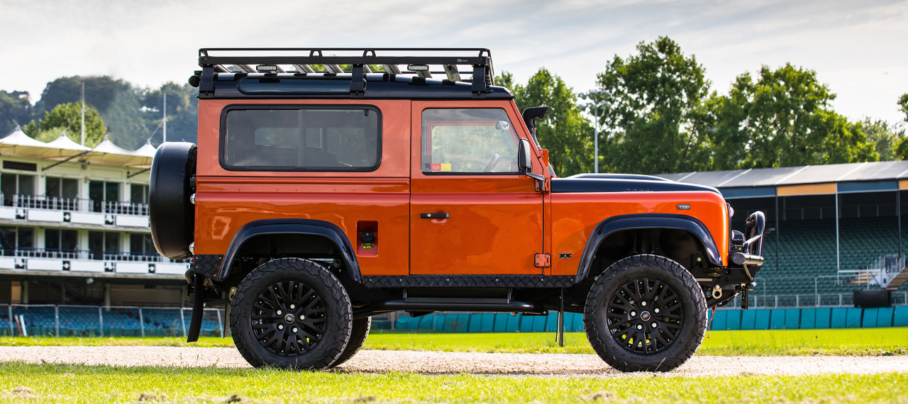 Side view of an orange Defender on a rugby pitch