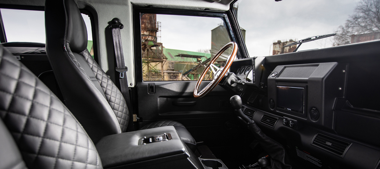 Interior view of Defender front seats with wooden steering wheel
