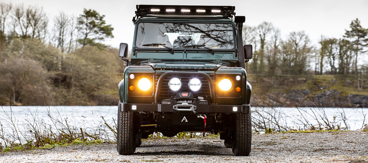 Front view of a D110 with WARN winch, HELLA spotlights and Trucklite headlights turned on